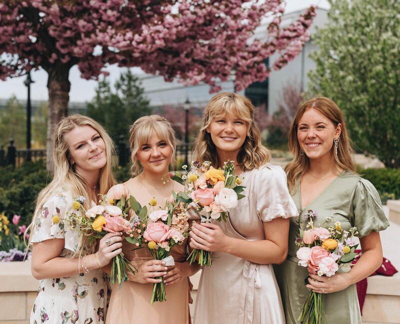 Bridesmaids pose with their flowers in their mismatched bridesmaid dresses